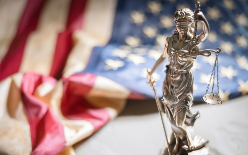 A statue of lady justice beside an American flag