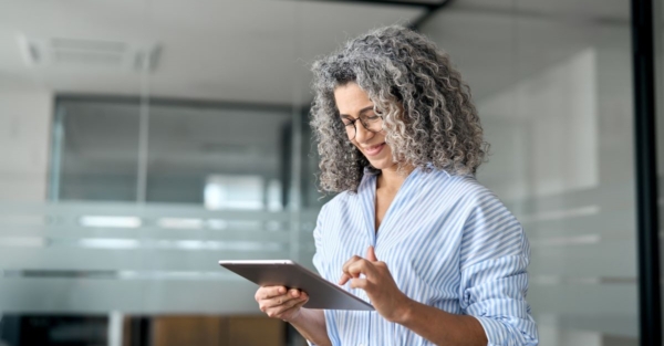 A mature professional woman smiles while using a tablet.